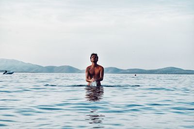 Portrait of shirtless man in swimming pool against sea