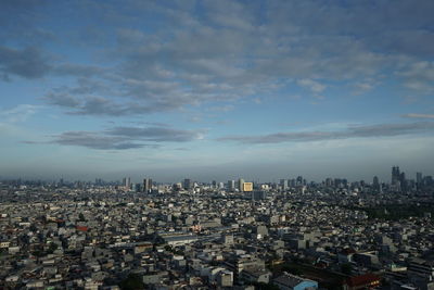 High angle view of city buildings against cloudy sky