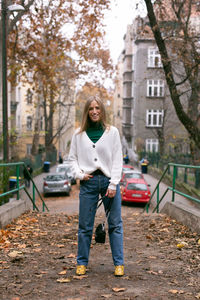 Portrait of woman standing against trees in city