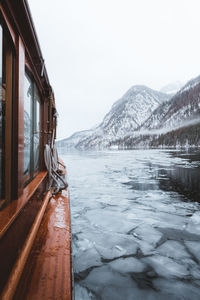 Frozen lake by snowcapped mountains against sky