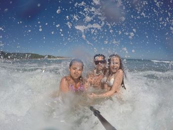 Family swimming in sea against sky