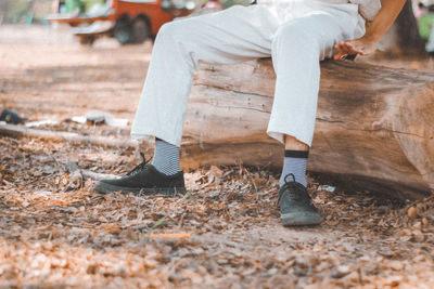 Low section of person sitting on log