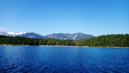 Scenic view of lake and mountains against blue sky