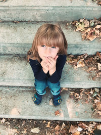 Smiling boy looking away while sitting on staircase