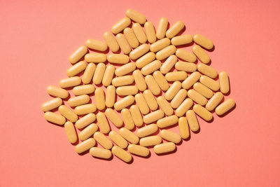 Many yellow pills on a pink background