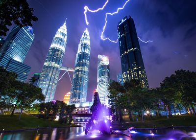 Low angle view of illuminated buildings against sky at night