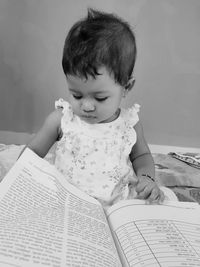 Girl with book sitting on bed at home