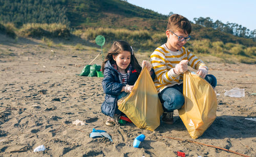 Siblings picking garbage at beach