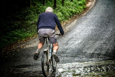 Rear view of a man bicycling on road