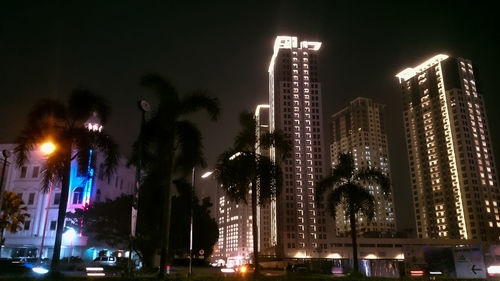 Low angle view of illuminated buildings against sky at night