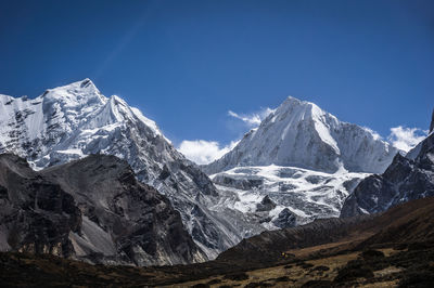 Scenic view of snowcapped mountains against blue sky