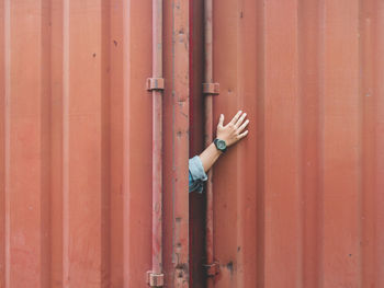 Close-up of human hand by metal door