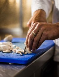 Midsection of man cutting mushroom in kitchen