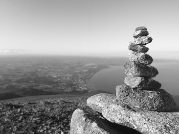 Stack of stones on rock by sea against sky