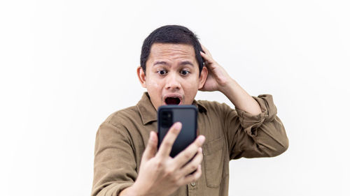 Portrait of man using mobile phone against white background