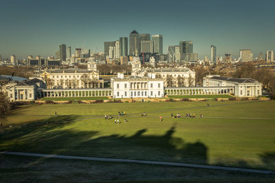Greenwich museum in a sunny day, with people in the park and the city of london behind
