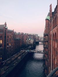 Canal amidst buildings in city against sky during sunset