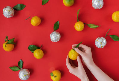 Hands making natural organic christmas toys from tangerines with green leaves. xmas celebration