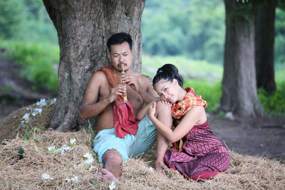 Full length of woman sitting on tree trunk