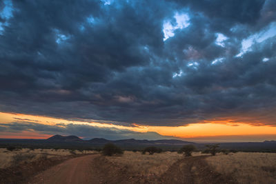 Scenic view of dramatic sky over field during sunset