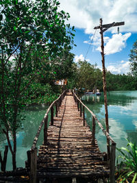 Footbridge over lake against sky