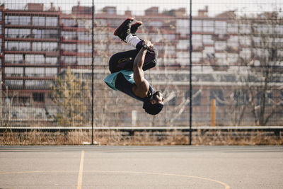 Young man practicing acrobats on sports court during sunny day