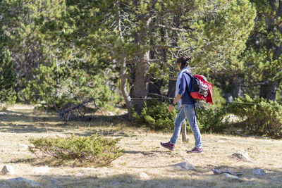 Side view of woman with backpack walking in forest