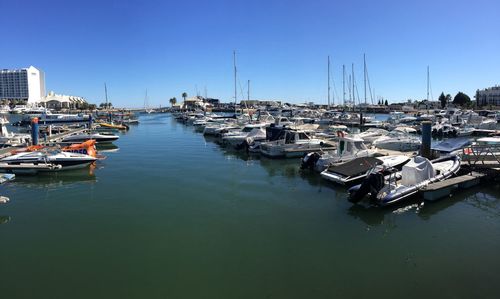 Boats moored at harbor against clear sky