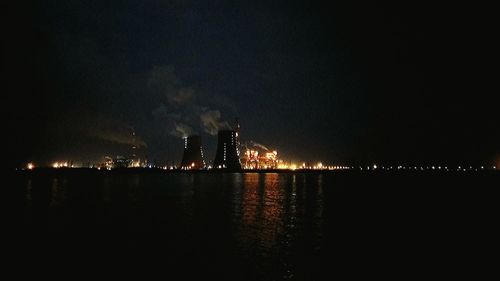 Illuminated smoke emitting from factory against clear sky at night