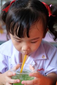 Close-up portrait of cute girl drinking glass