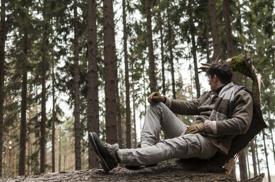 Young man sitting on log in forest