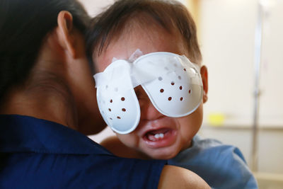 Close-up of mother carrying baby boy with bandage on eyes