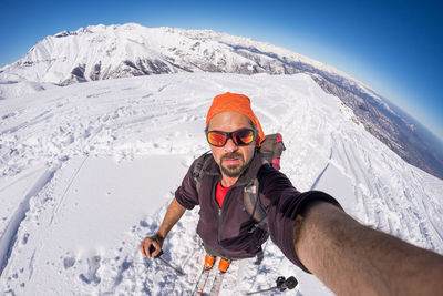 Portrait of man taking selfie while standing on snowy field
