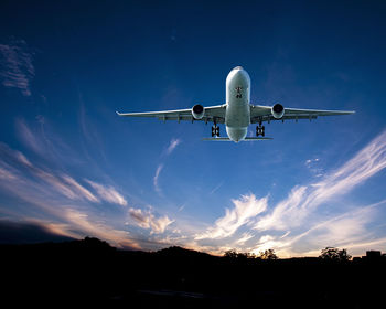 Low angle view of airplane flying against sky during sunset