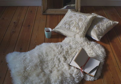 High angle view of book on white rug over hardwood floor at home