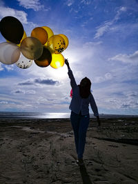 Full length of woman standing at beach against sky