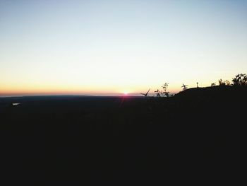 Scenic view of silhouette beach against clear sky during sunset