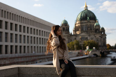 Woman sitting on bridge against sky