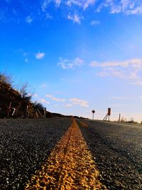 Yellow marking on empty road against blue sky