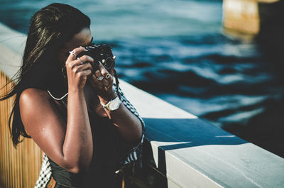 Midsection of woman photographing by swimming pool