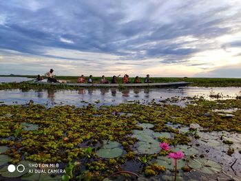 Scenic view of lake against cloudy sky during sunset