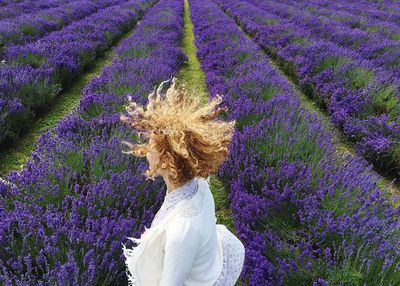 High angle view of woman with curly hair jumping in lavender field