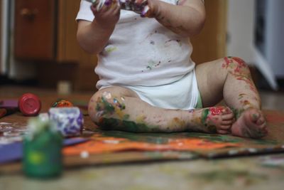 Low section of messy baby boy playing with paint at home