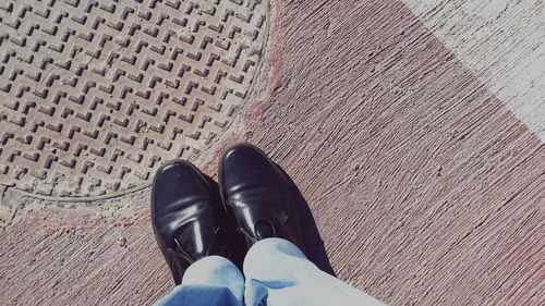 Low section of man standing by manhole lid on footpath