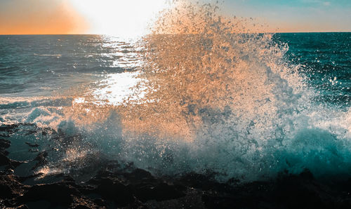 Close-up of sea waves against sky at sunset