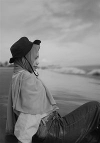 Side view of young woman looking at sea against sky