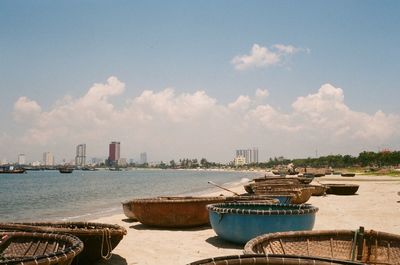 Fishing baskets at beach in city against sky