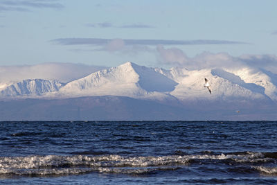 Scenic view of sea and snowcapped mountains against sky