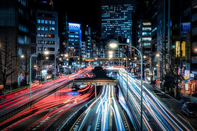 Light trails on city street amidst buildings at night