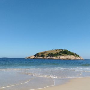 Scenic view of beach against clear blue sky